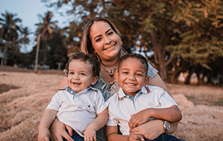 woman holding 2 young boys smiling